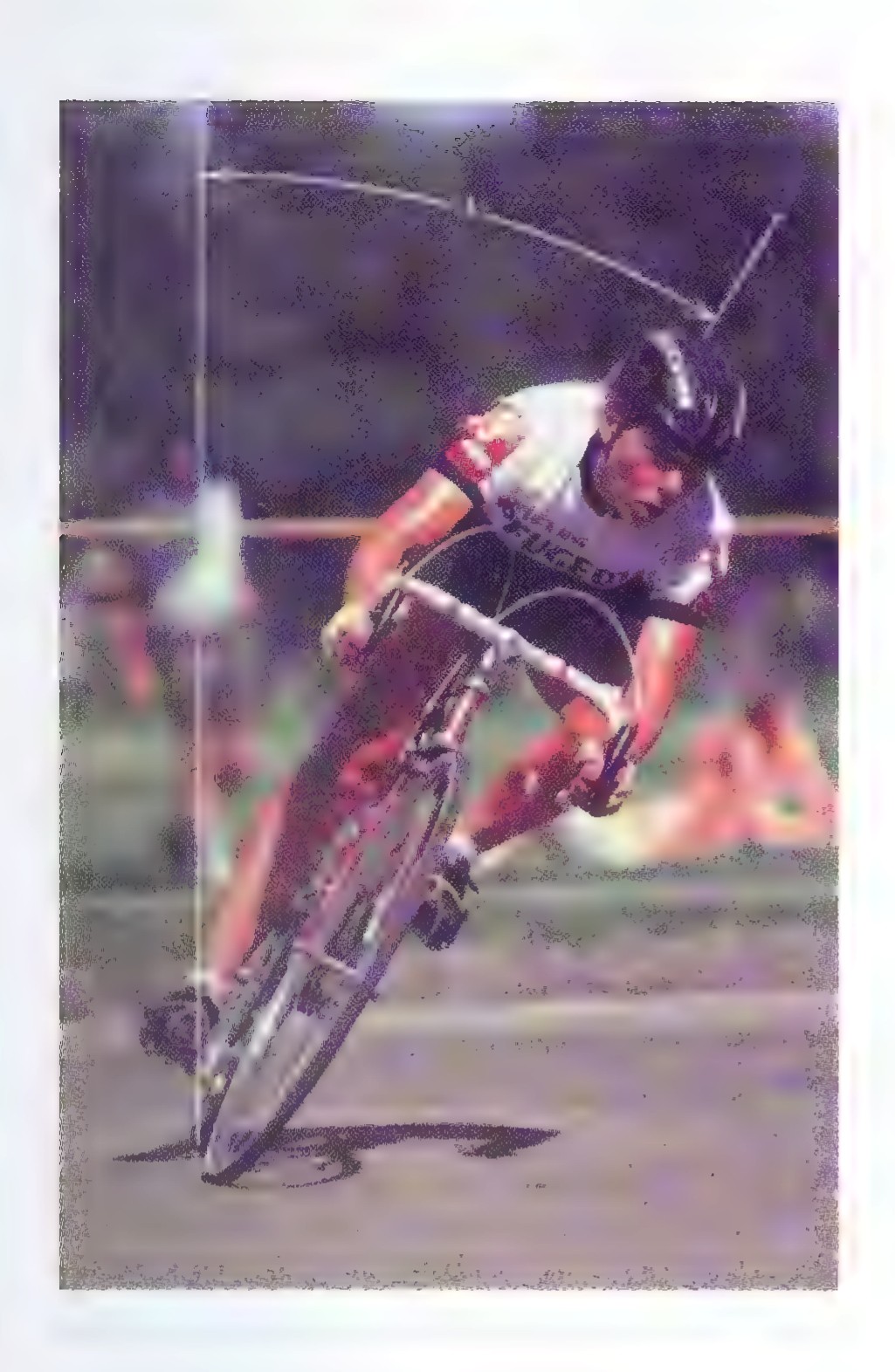 A photograph of a cyclist leaning sharply to the left as he rides around a velodrome track.