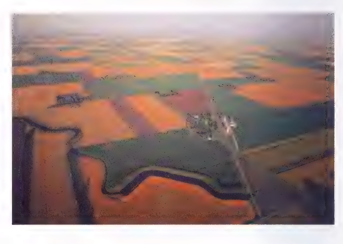 An aerial photograph of farmland near Castleton, North Dakota, with a road and a railroad crossing at a sharp angle.