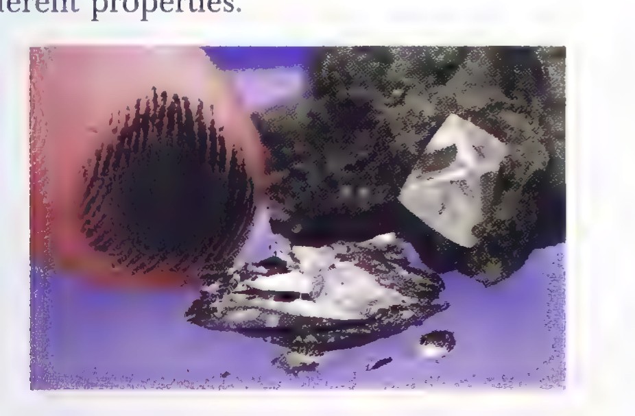 A photograph of a dark graphite crystal beside a clear diamond crystal on a rock.