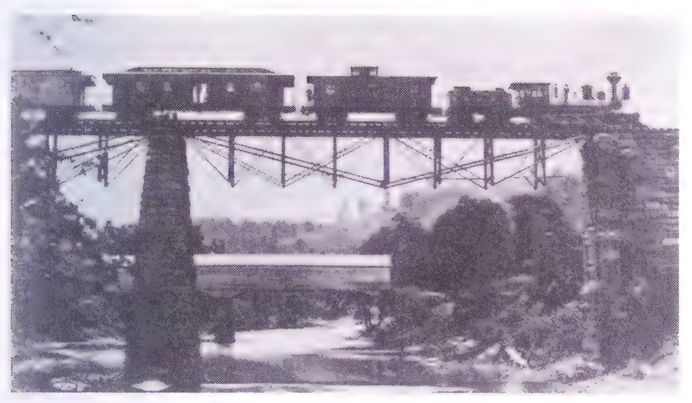 Photograph of a high railroad trestle bridge crossing a valley, supported by a framework of wooden trusses.