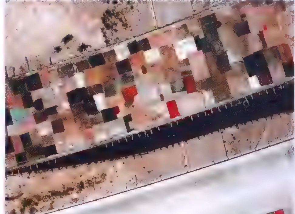 Aerial photograph of a freeway overpass under construction, with stacks of old carpets laid on the fresh concrete.