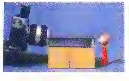 Small photograph of a toy kaleidoscope with two mirrors and a peephole, standing on a table.