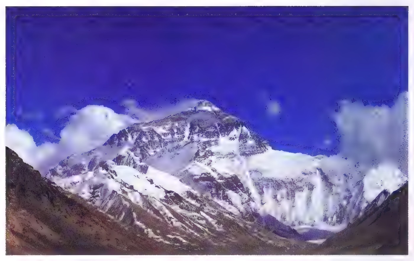 Photograph of Mount Everest: the snow-covered summit and ridge rising above clouds, seen from a neighboring slope.