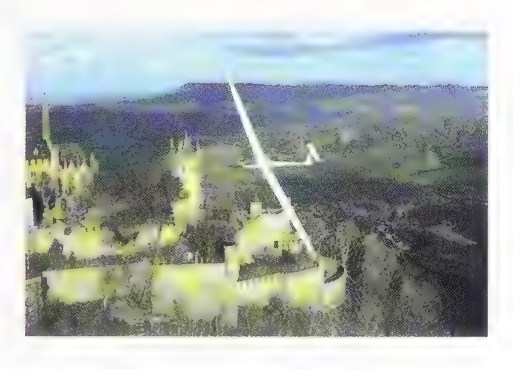 Photograph of a sailplane in flight over a hilly landscape, with a long white line drawn along its glide path.