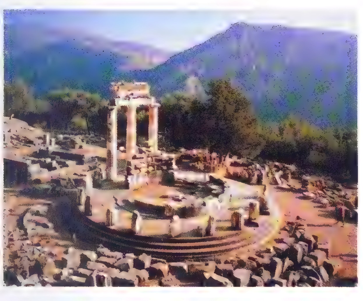 Photograph of the ruins of the Tholos at Delphi: a circular temple platform with three standing columns among fallen stones, mountains behind.