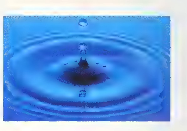Concentric circular ripples spreading on blue water after a drop falls, with the drop caught mid-splash.