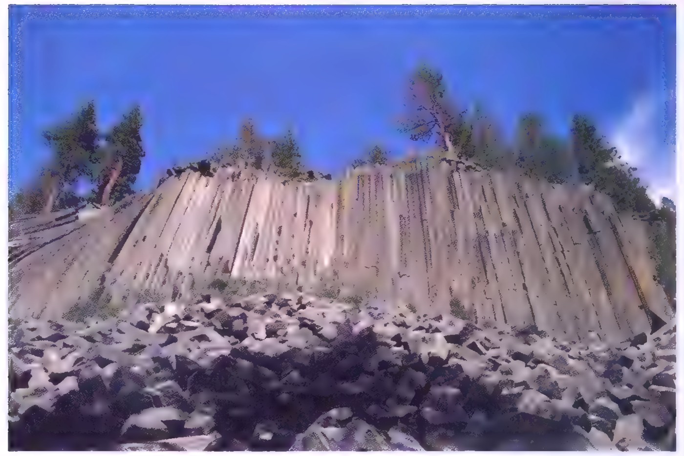 Photograph of the Devil’s Post Pile: a wall of tall, closely packed columns of rock with pentagonal and hexagonal cross sections.