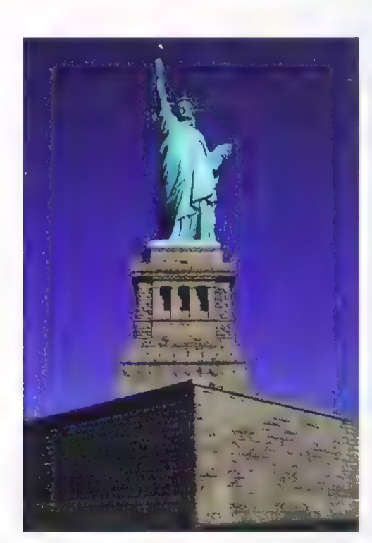 Photograph of the Statue of Liberty at night, lit green against a dark blue sky.