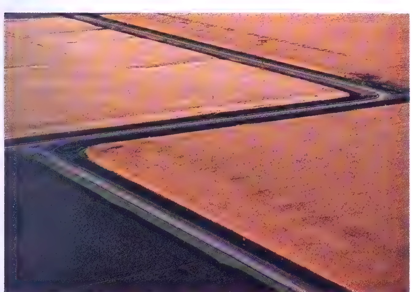 Aerial photograph of a straight road crossing flat farmland, with a small offset where the road jogs sideways.